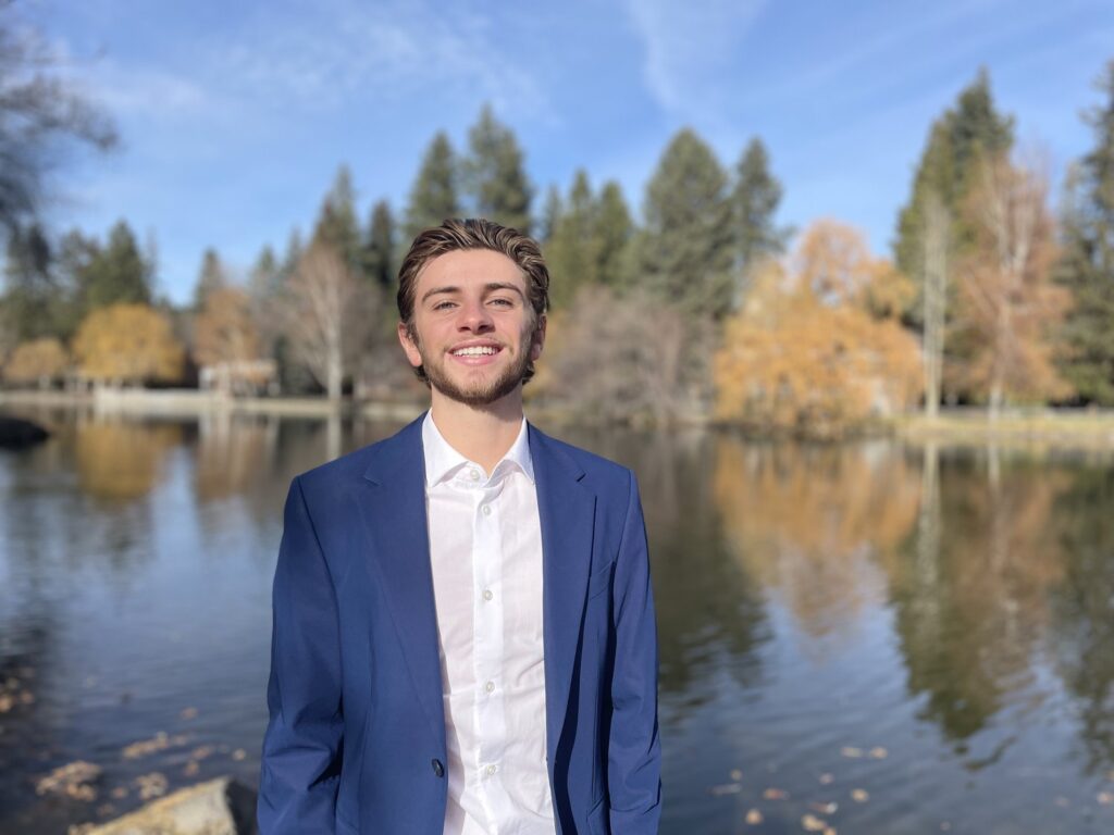 Image of Elliot smiling with a lake behind him